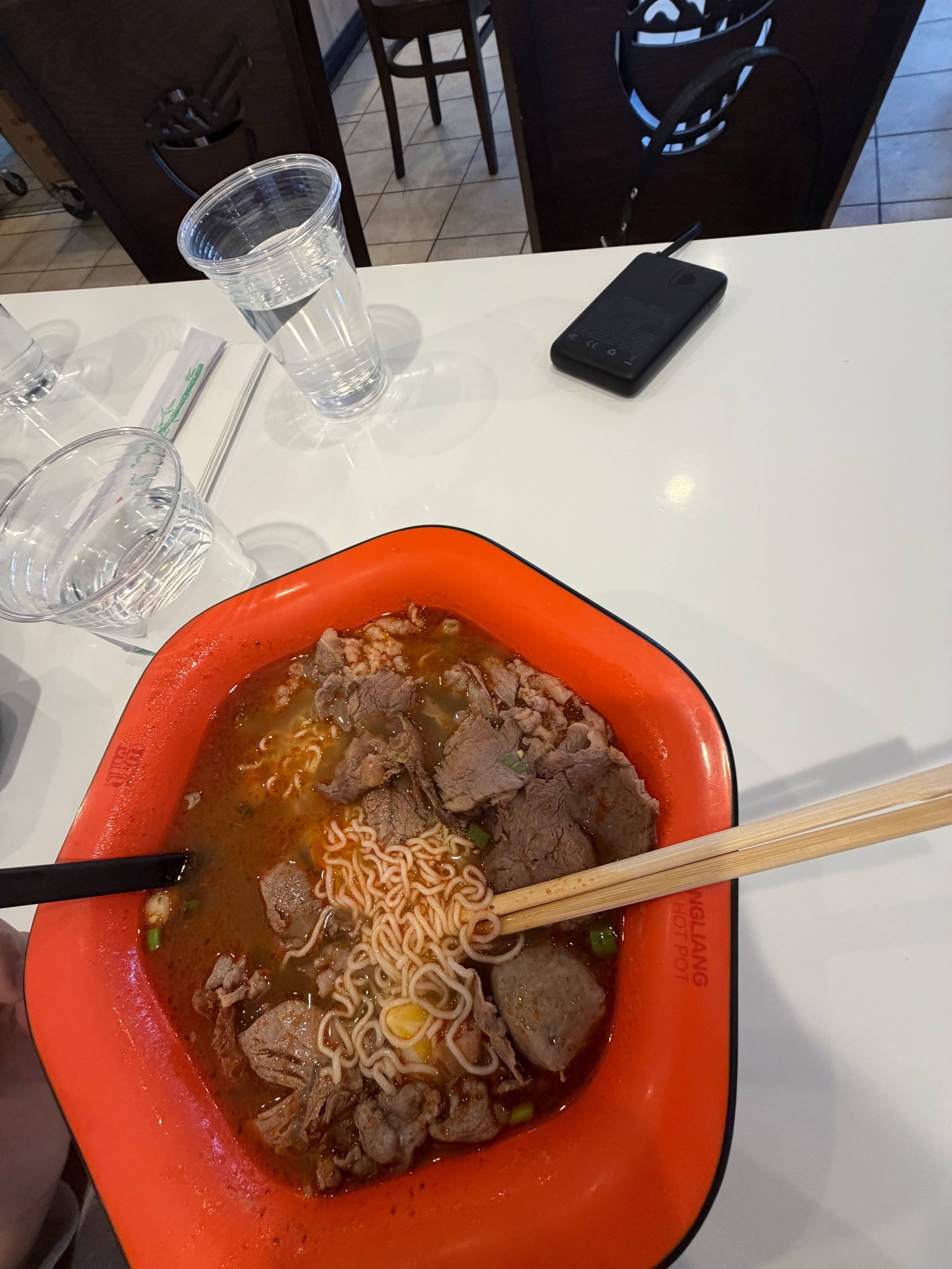 Spicy beef noodle soup in an orange bowl