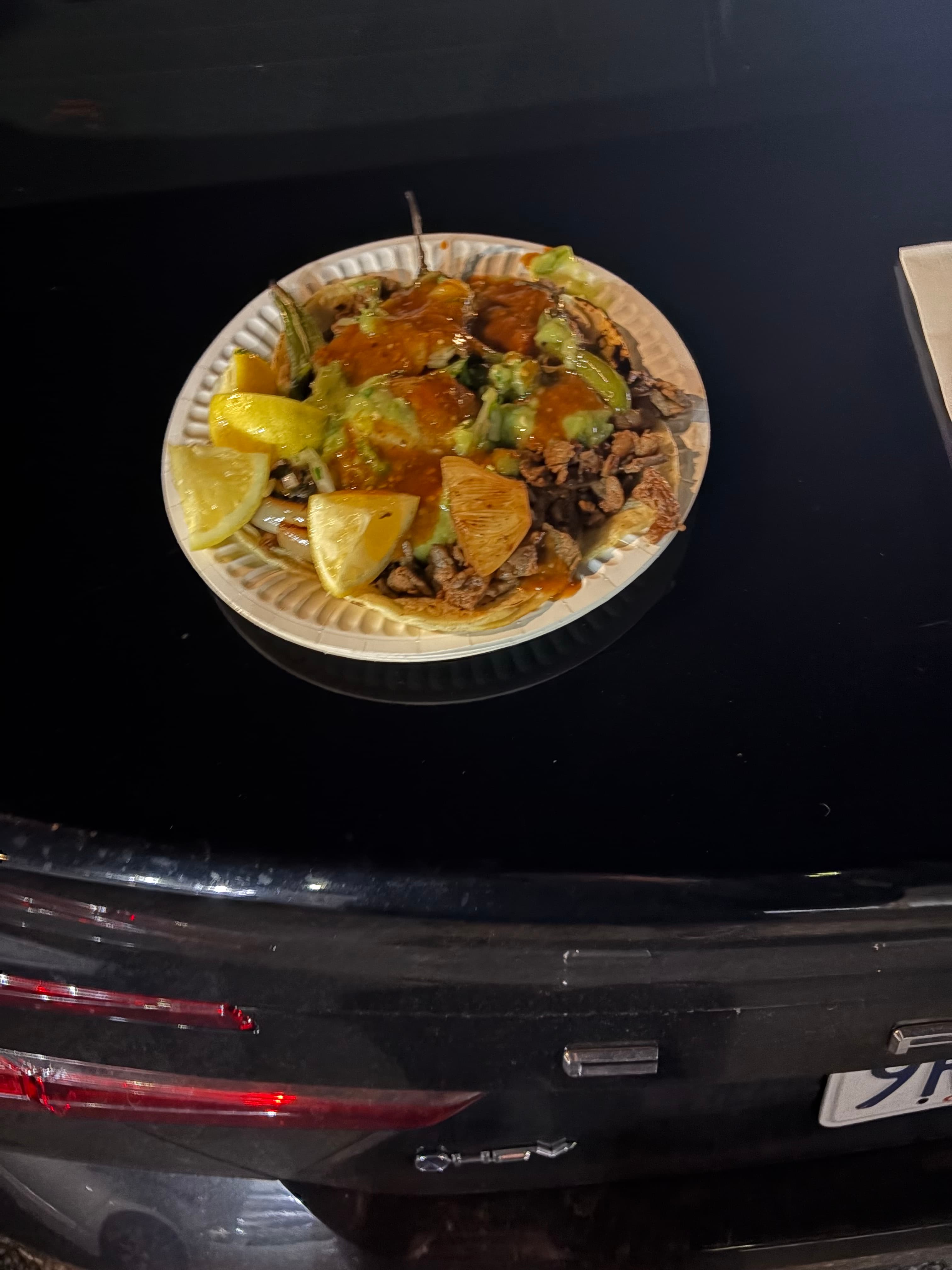 Street tacos with salsa and lemon on a car trunk