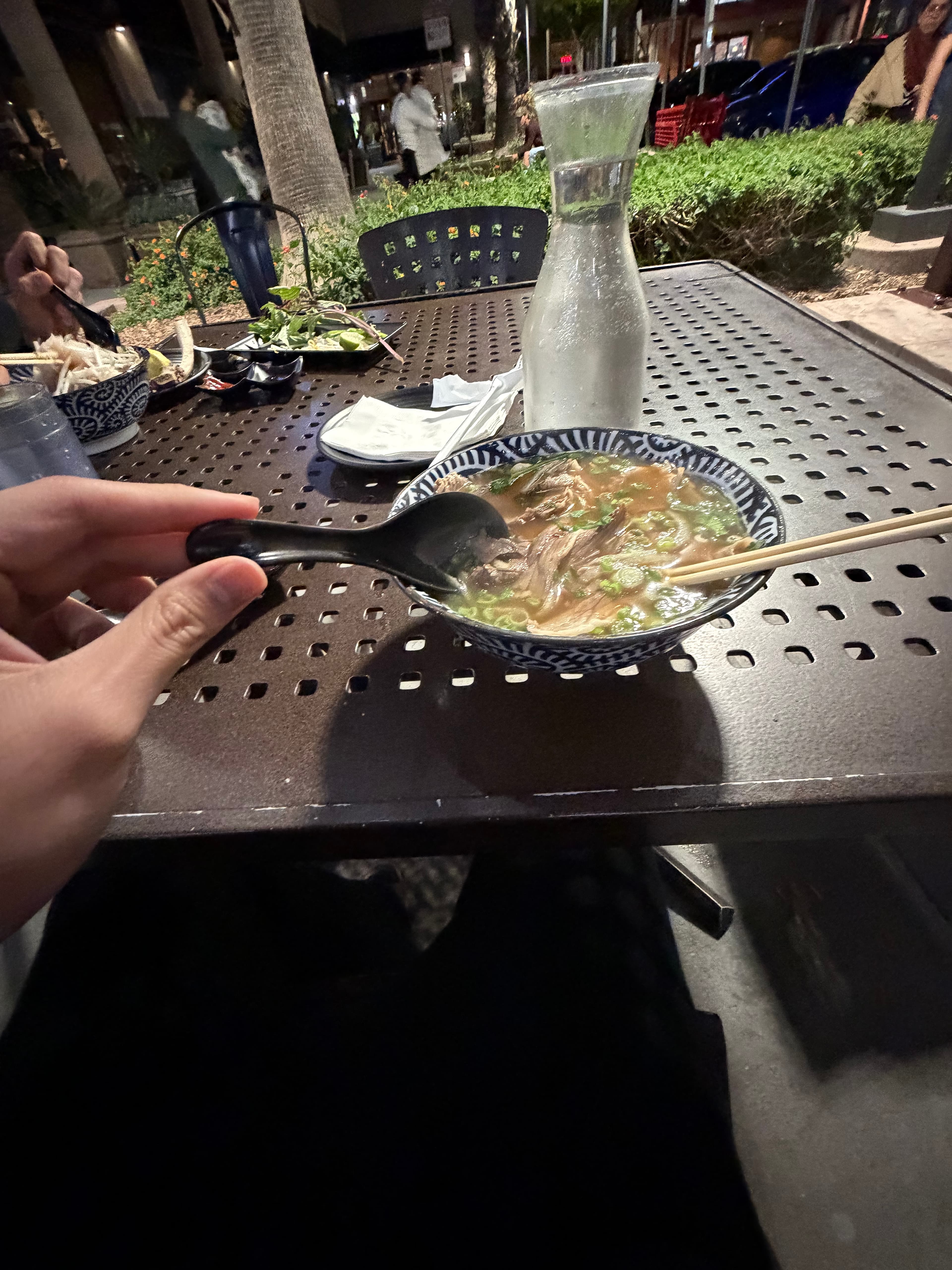 Bowl of pho on an outdoor table at night