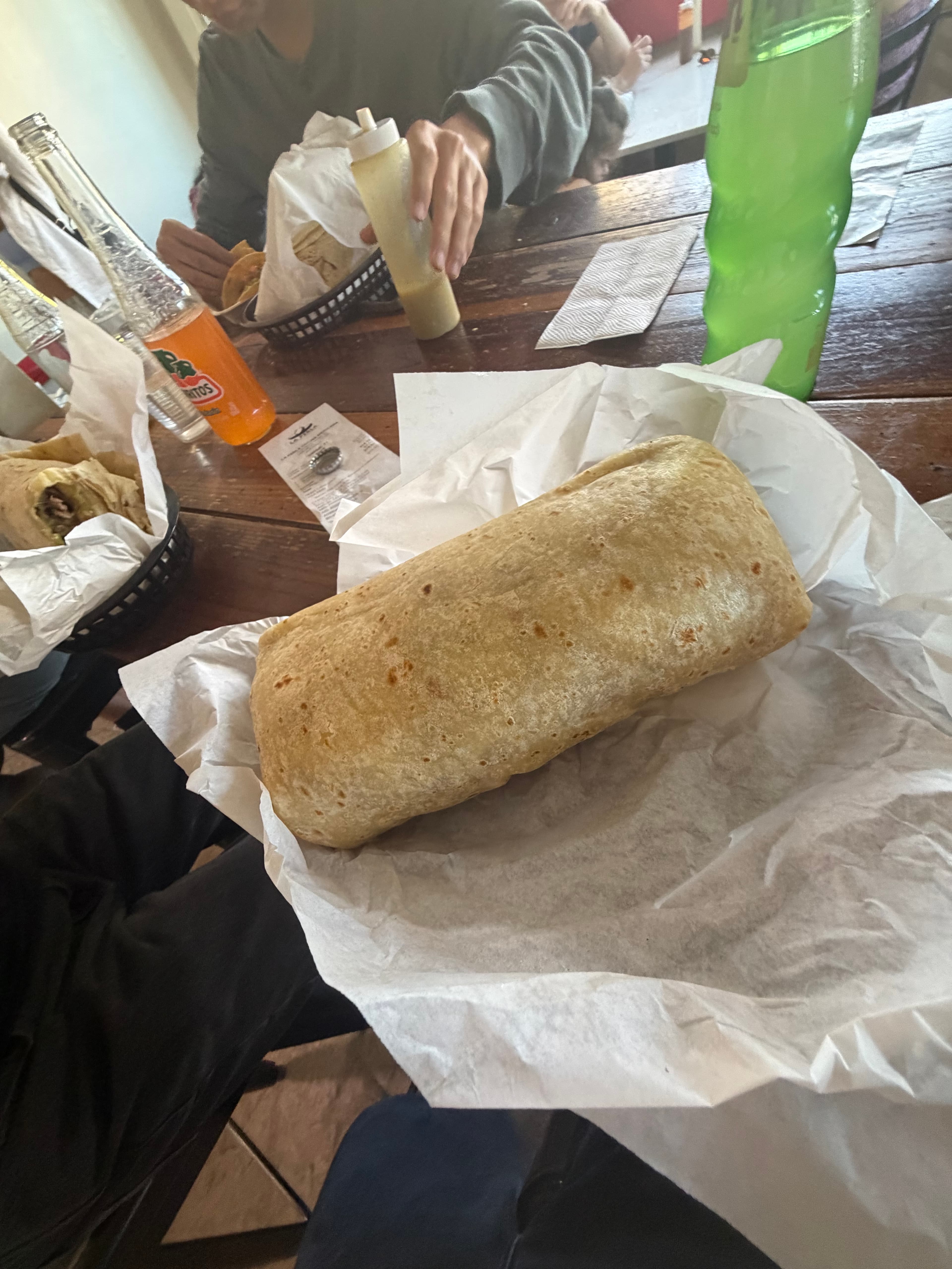 Large burrito on parchment with bottled drinks