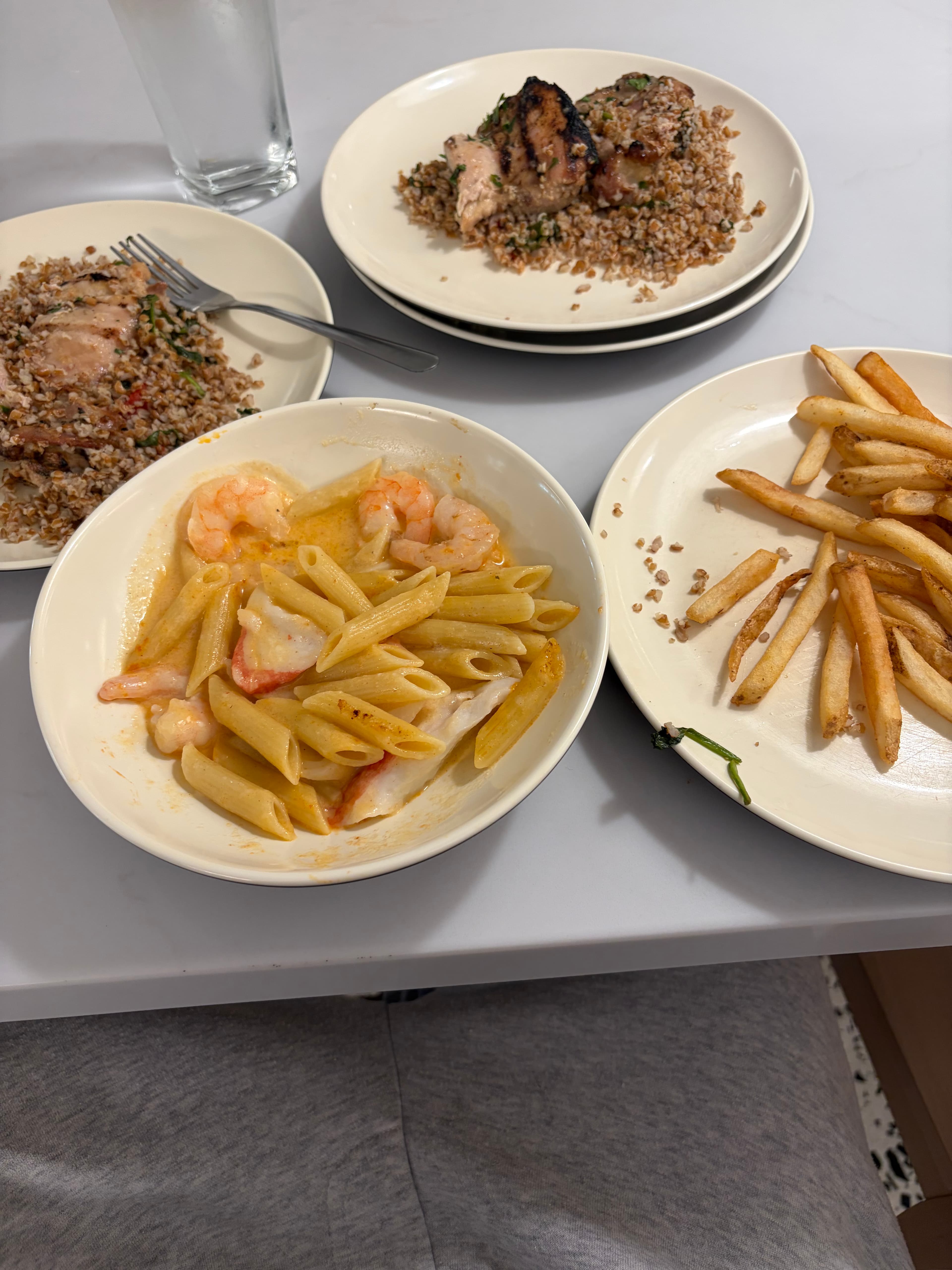 Pasta, shrimp, fries, and grain plates on a table